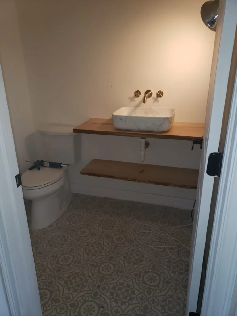 Completed bathroom remodel featuring floating wood vanity, vessel sink, wall-mounted gold faucet and patterned tile floor, New Port Richey FL — Power Contractor Group