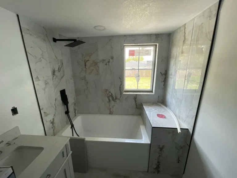 Completed luxury bathroom renovation with marble-look tile walls, freestanding soaking tub and black rain shower fixture, Tampa Bay FL — Power Contractor Group, CGC1539545