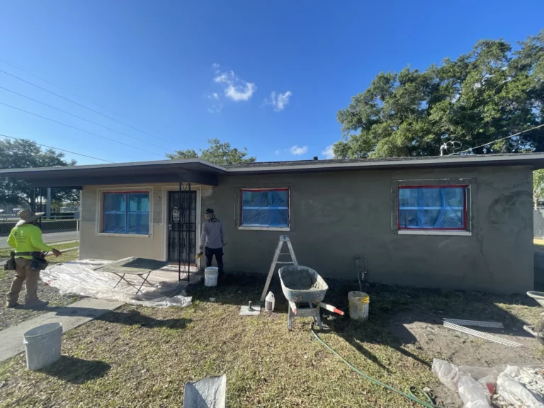 Crew applying fresh stucco coating to concrete block home exterior during residential renovation in Tampa Bay, FL — Power Contractor Group, CGC1539545
