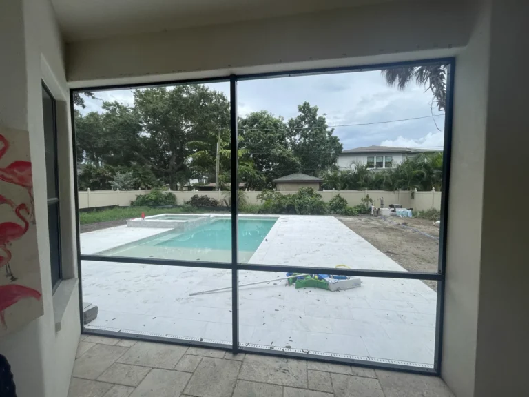 New Florida room with screen enclosure looking out to pool and travertine paver patio during construction, Tampa Bay FL — Power Contractor Group, CGC1539545