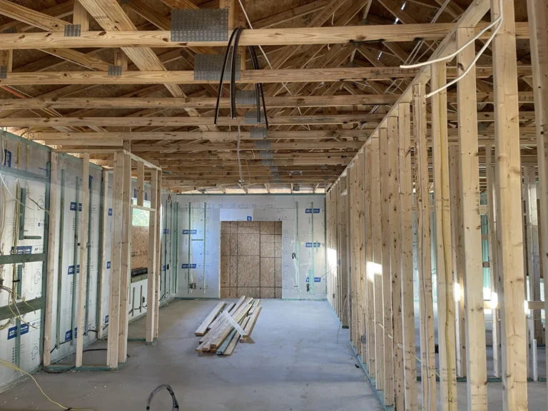 Open interior framing of large new construction building showing wood trusses, stud walls and insulation, Tampa Bay FL — Power Contractor Group