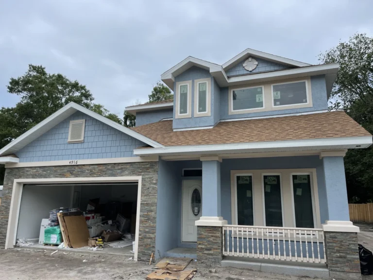 Completed new two-story craftsman home with blue-gray paint, shingle roof, stone veneer base and two-car garage, Tampa Bay FL — Power Contractor Group, CGC1539545