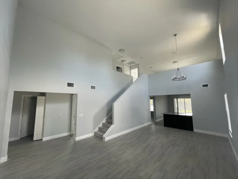 Newly built two-story home interior showing open living area, staircase, engineered hardwood floors and chandelier, Tampa Bay FL — Power Contractor Group