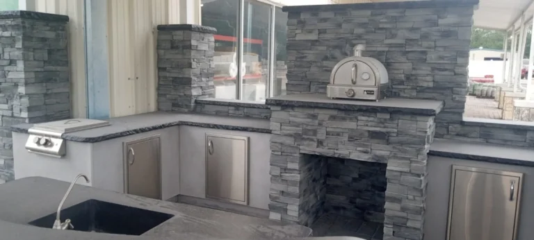 Full outdoor kitchen and entertainment area with L-shaped concrete countertop, built-in grill, stone veneer fireplace and pizza oven, Tampa Bay FL — Power Contractor Group