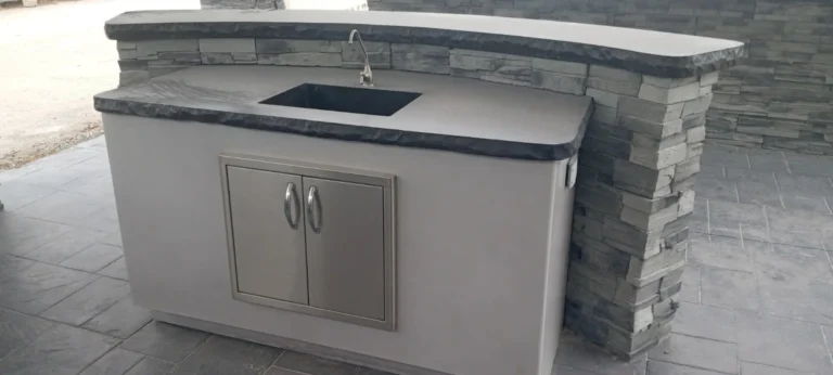 Custom outdoor kitchen with stone veneer columns, concrete countertop, stainless steel cabinets and sink built on travertine pavers, Tampa Bay FL — Power Contractor Group