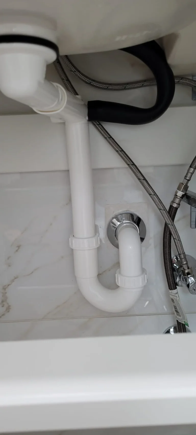 Certified plumber installing P-trap drain and braided supply lines under bathroom sink, New Port Richey FL — Power Contractor Group, CFC1434028