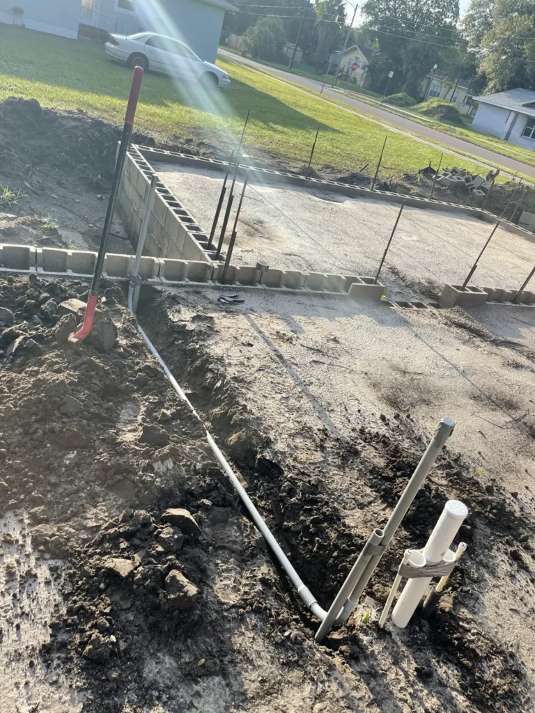 PVC drain and supply lines installed through concrete block footer and trench at new construction site in Tampa Bay FL — Power Contractor Group, CFC1434028